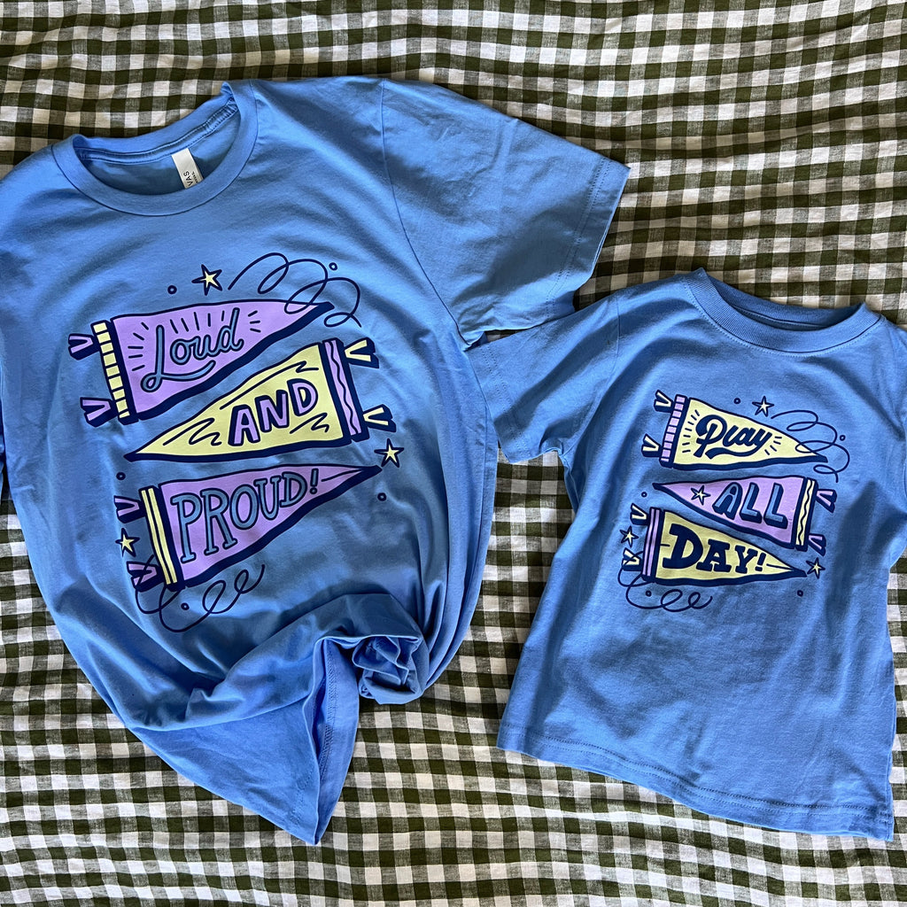 Two blue t-shirts with colorful graphics on a checkered fabric background